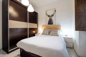 A bedroom with a bed, nightstands, a wooden headboard, a large mirror, and a wall-mounted deer head artwork. - Córdoba Center Monumental Home (Cordoba)