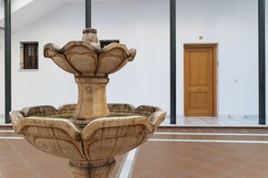 A stone fountain with a fluted design in front of a white building with a wooden door and windows. - Córdoba Center Monumental Home (Cordoba)
