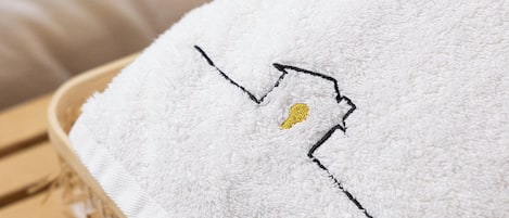 A white towel with a black and yellow embroidered design, placed on a woven basket.