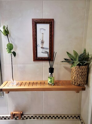 A wooden shelf with a framed artwork, a glass vase with a plant, and a woven pot. - Córdoba Center Monumental Home (Cordoba)