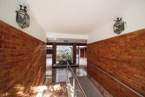 A hallway with brick walls, a marble floor, and two wall-mounted lanterns. - La Casa de la Musica - A unos pasos de la Mezquita (Cordoba)