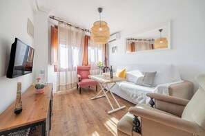 Ett modernt vardagsrum med en soffa, fåtöljer, ett soffbord, en tv och ett matbord.