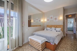 A bedroom with a bed, a bedside table, a mirror, and a view of the outside. - Cozy Retreat with Patio Steps from Alcázar (Cordoba)