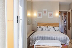 Ein Schlafzimmer mit einem Bett, Nachttischen, Wandleuchten und gerahmten Pflanzenbildern.