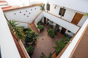 Ein Innenhof mit Fliesenboden, Pflanzkübeln und einer Treppe zu einer oberen Ebene.