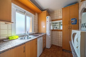 Eine kompakte Küche mit Holzschränken, einem eingebauten Geschirrspüler und einem Kühlschrank.