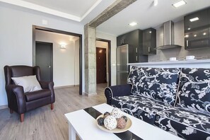 A modern living room with a leather armchair, a patterned sofa, and a coffee table with decorative items. - Casa Maryna Malaga - Three Bedroom Apartment, Sleeps 5 (Malaga)