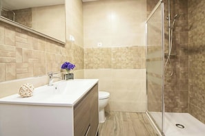 A modern bathroom with a glass shower enclosure, a white sink, and a toilet. - Casa Maryna Malaga - Three Bedroom Apartment, Sleeps 5 (Malaga)