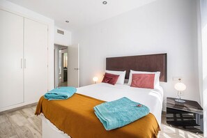 Ein Hotelzimmer mit einem Bett, zwei Nachttischlampen, einem Nachttisch und einem Kleiderschrank.