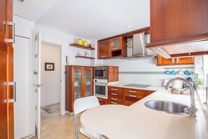 Cocina compacta con muebles de madera, microondas, horno y lavabo.