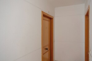 Eine geschlossene Holztür in einem Raum mit weißen Wänden und einer sichtbaren Steckdose an der Wand.