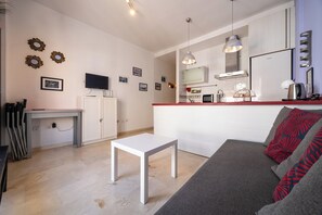 Ein modernes Wohnzimmer mit Küchenbereich, einem Esstisch und einer Couch mit Zierkissen.