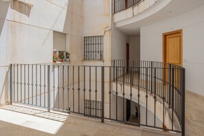 Ein mehrstöckiger Innenraum mit Treppe, Metallgeländern und einer Holztür.