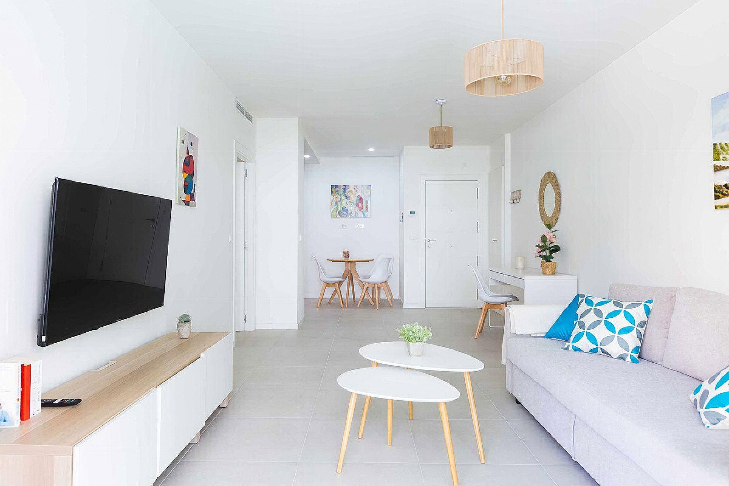 Un salon moderne doté d’un téléviseur à écran plat, d’un canapé, d’une table basse et d’un coin repas avec des chaises et une table.