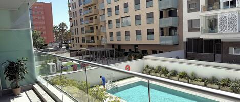 A modern apartment building with a swimming pool and a covered outdoor area.