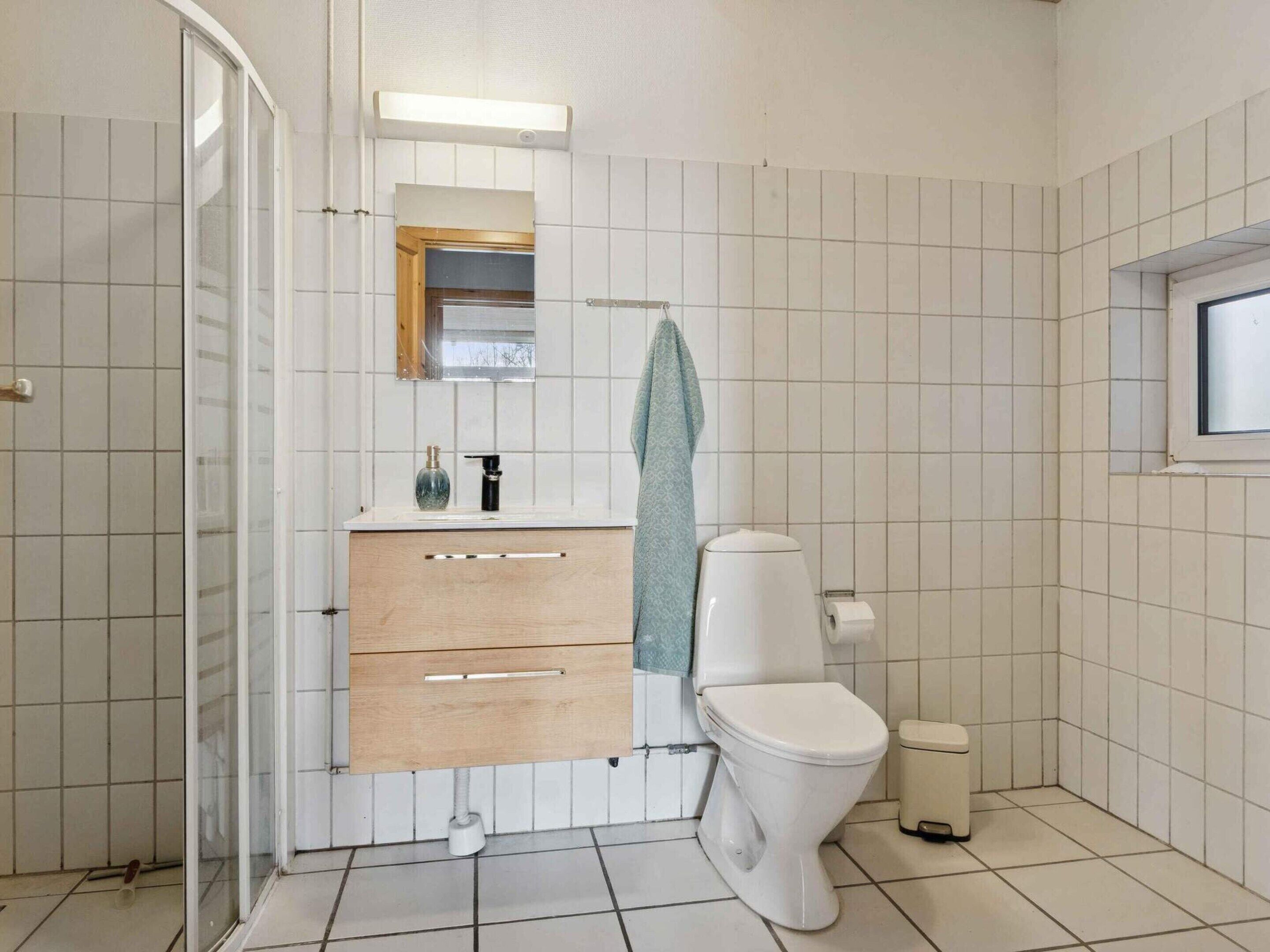 A bathroom with a toilet, a sink, a mirror, and a towel rack.