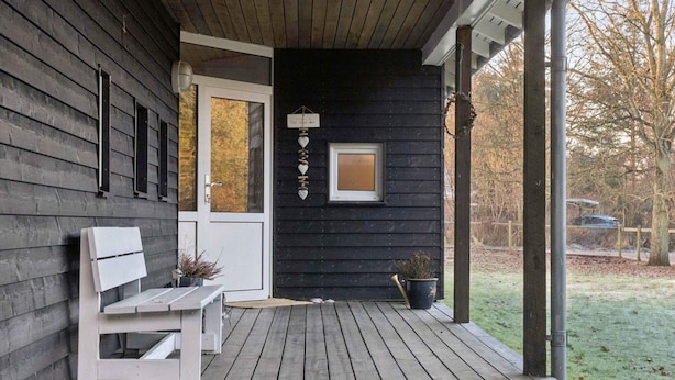 A wooden deck with a bench, a door, and a small window. - 4 Star Holiday Home in Vig (Vig)