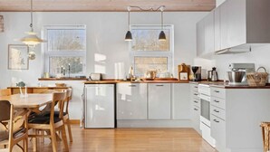 A modern kitchen with white cabinets, wooden countertops, and pendant lighting. - 4 Star Holiday Home in Vig (Vig)