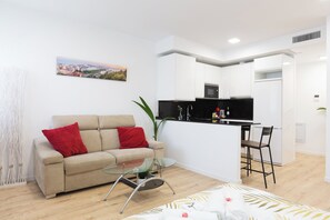 A modern living room with a sofa, a glass coffee table, and a view of a cityscape. - Cosmopolitan Loft & Malaga Beach (Málaga)