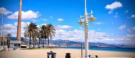Une plage bordée de palmiers, une haute structure et un ciel bleu azur.