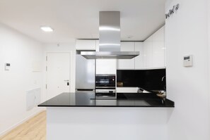 A modern kitchen with a central island, built-in oven, and stainless steel range hood. - Cosmopolitan Apt & Malaga Beach (Málaga)