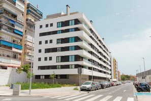 A multi-story residential building with balconies, a parking lot, and a clear sky. - Cosmopolitan Apt & Malaga Beach (Málaga)