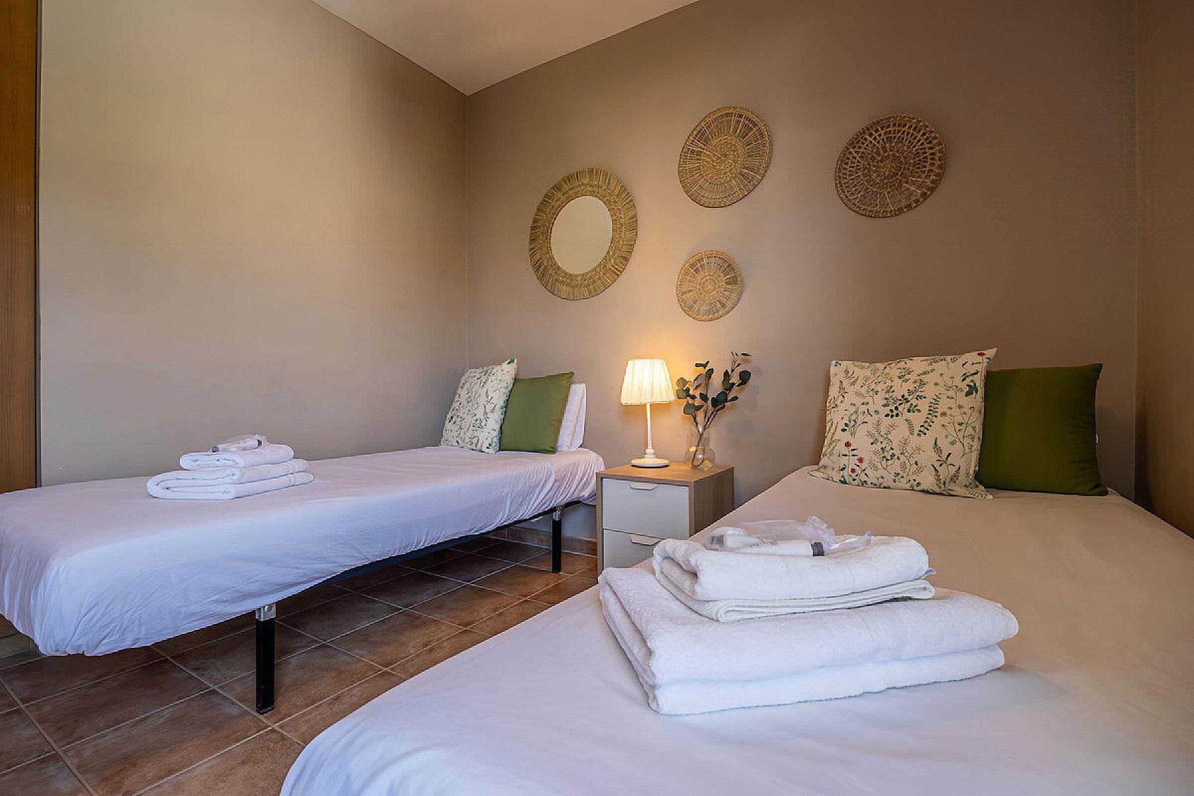 A hotel room with two beds, a nightstand, and decorative wall art.