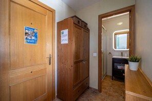 Ein Korridor mit Holztüren, einem Schrank und einem Badezimmer mit Waschbecken und Topfpflanze.