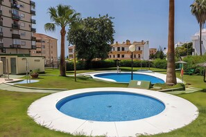 Ett bostadsområde med en swimmingpool, palmer och en byggnad med balkonger.