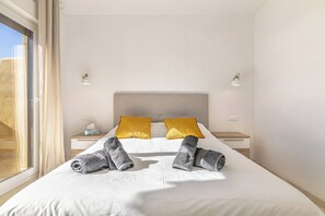 Ein Hotelzimmer mit einem großen Bett, zwei Nachttischen, einem Fenster und Blick ins Freie.