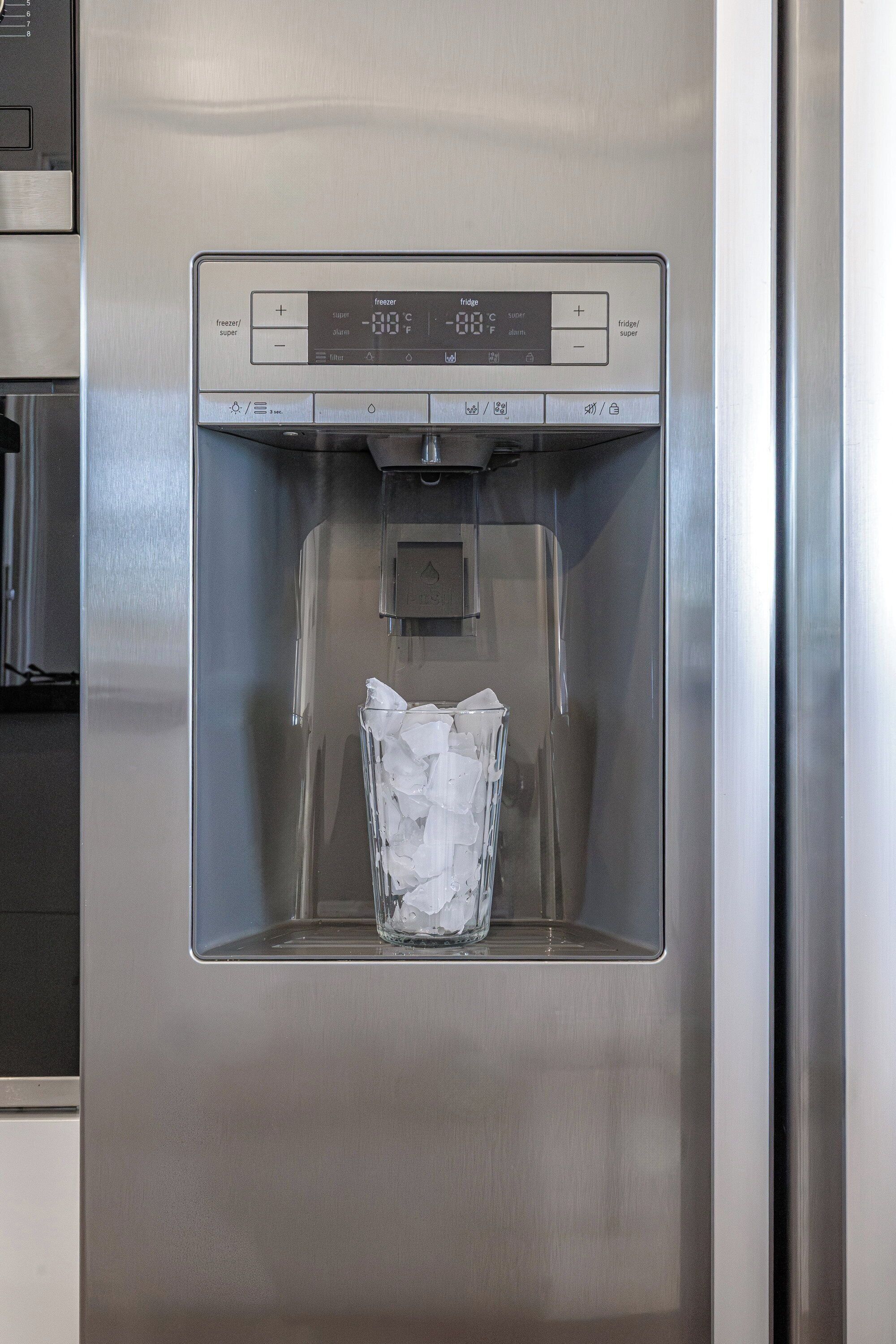 Dispensador de agua de acero inoxidable con un recipiente de vidrio para hielo.