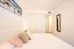 A hotel room with a bed, pillows, a nightstand, a wall-mounted picture, and a door leading to another room. - Tradiciones Marineras, Puerto y Plaza de Toros (Estepona)