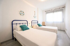 Habitación de hotel con dos camas individuales, una ventana con cortinas y decoración de temática náutica.