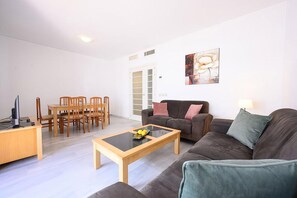 A modern living room with a wooden dining table, a sofa, and a coffee table. - Tradiciones Marineras, Puerto y Plaza de Toros (Estepona)