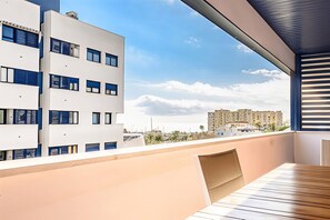 Un balcón moderno con vistas a un paisaje urbano, que muestra un edificio con múltiples ventanas y un cielo despejado.