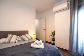 A hotel room with a bed, a bedside lamp, an air conditioning unit, and a potted plant. - Casa Toril & Esparto de la Corredera (Cordoba)