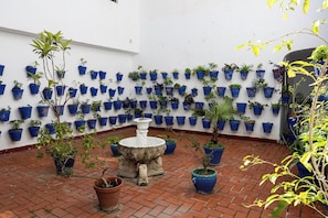 A courtyard with a white wall adorned with numerous blue planters containing various plants. - Casa Toril & Esparto de la Corredera (Cordoba)