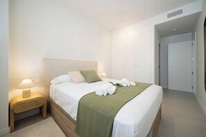 A hotel room with a bed, bedside lamps, a green throw blanket, and neatly folded towels. - PAR 00 Golf Estepona (Estepona)