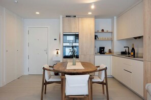 A modern kitchen with a wooden dining table, chairs, and built-in appliances. - PAR 00 Golf Estepona (Estepona)