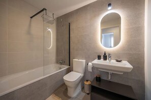 Et moderne badeværelse med en glasafskærmet brusekabine, toilet og et spejl med underskab.
