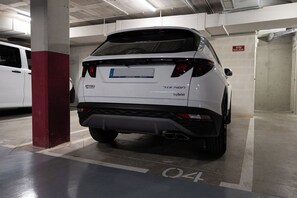 Ein weißer SUV steht in einer Parkgarage mit mehreren Ebenen.