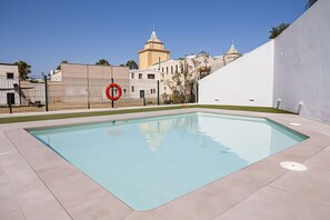 Ein Schwimmbecken mit umgebender Absperrung, einem Verbotsschild für Parkverbietung und Gebäuden im Hintergrund.