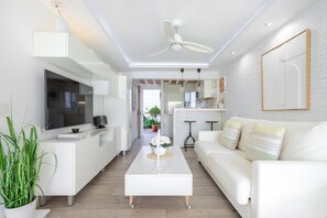 Een moderne woonkamer met een witte bank, een bijzettafeltje en een televisie.