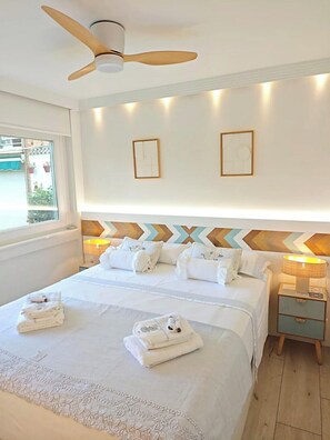 Ein Hotelzimmer mit einem Bett, einem Deckenventilator, Nachttischlampen und Blick ins Freie.