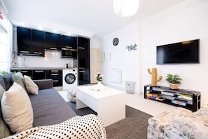 A modern living room with a sofa, coffee table, and a flat-screen TV. - Cordoba in Bloom Steps from Alcazar & Mosque (Cordoba)