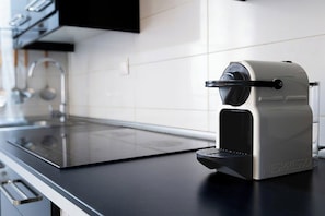 A modern kitchen with a built-in espresso machine, a stainless steel sink, and a black countertop. - Cordoba in Bloom Steps from Alcazar & Mosque (Cordoba)