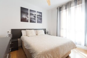 A modern bedroom with a large bed, bedside tables, a desk, and a window with curtains. - Tradiciones marineras, la Jabega del Palo (Málaga)