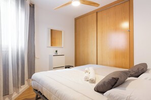 Ein Schlafzimmer mit einem Bett, einem Holzschrank, einem kleinen Tisch und einem Deckenventilator.