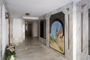 Un couloir aux murs de marbre orné d’une fresque représentant un bâtiment.