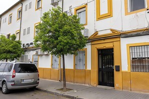 A residential building with a tree in front, a parked car, and a black door. - Calahorra Experience · Mezquita Frontline (Cordoba)